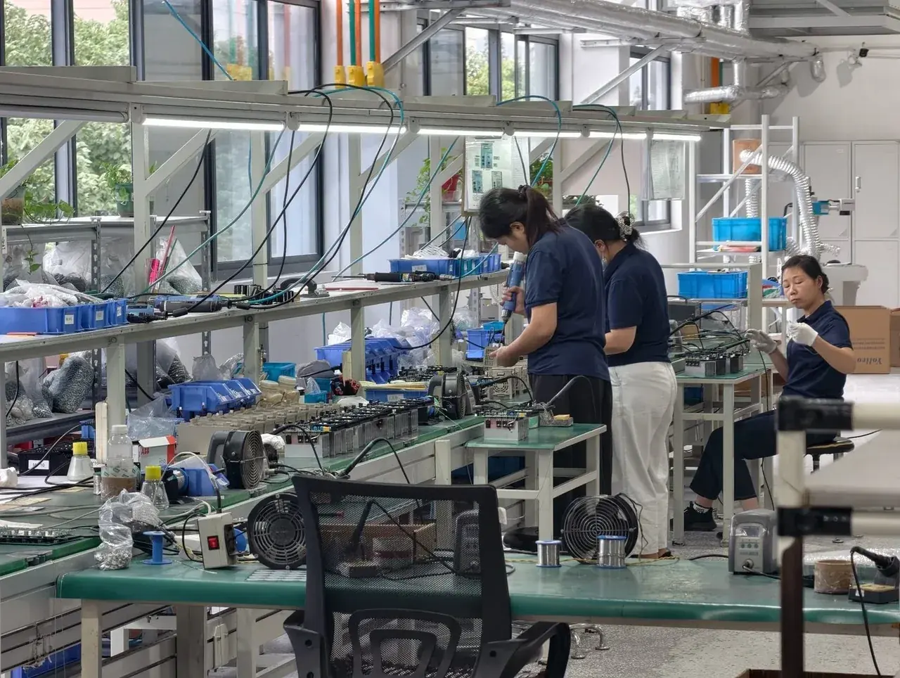 Operators assembling drives at workbenches along the assembly line